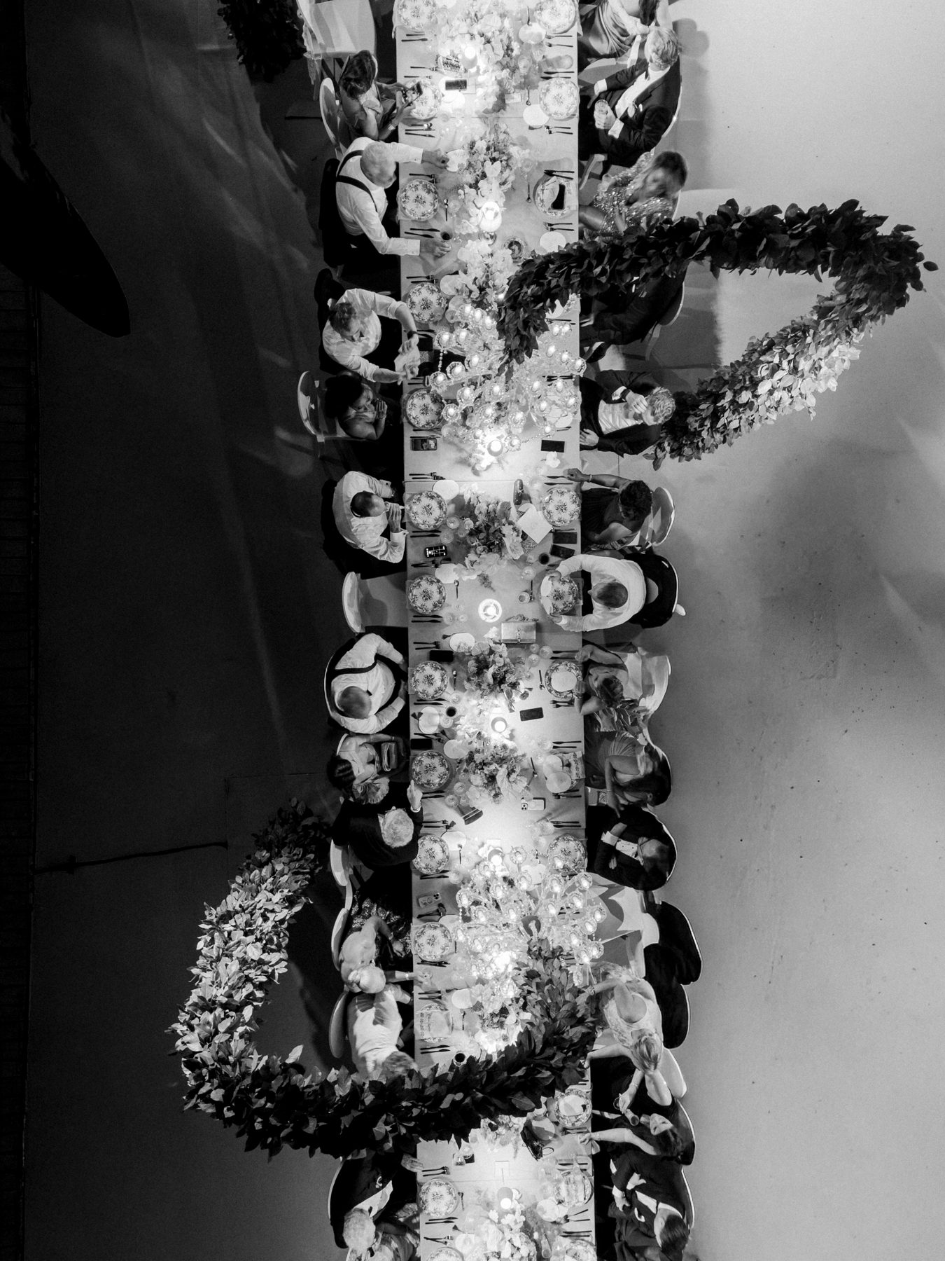 Black and white aerial of a long-table wedding dinner with crystal chandeliers, Curacao