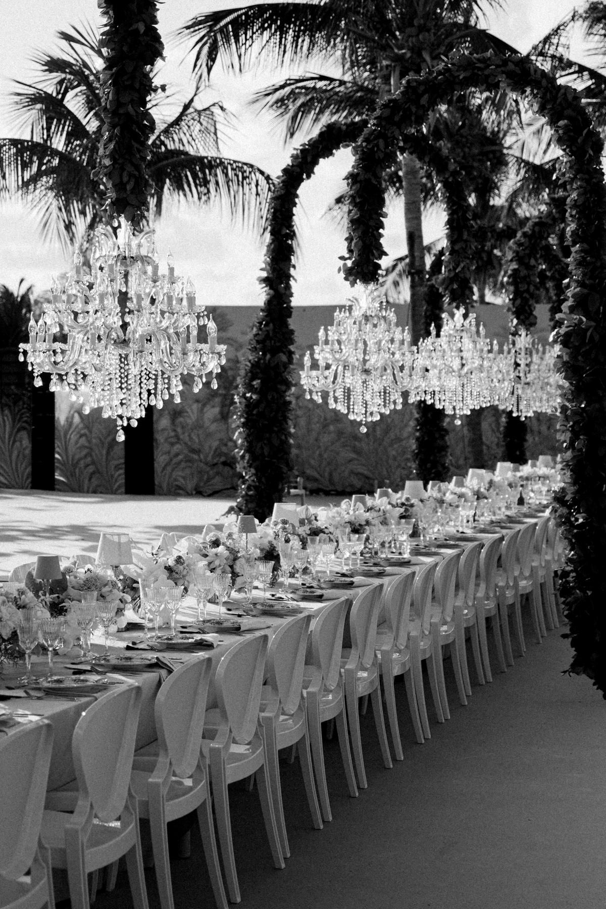 Black and white row of Maria Theresia crystal chandeliers beneath palms at a Curacao beach wedding