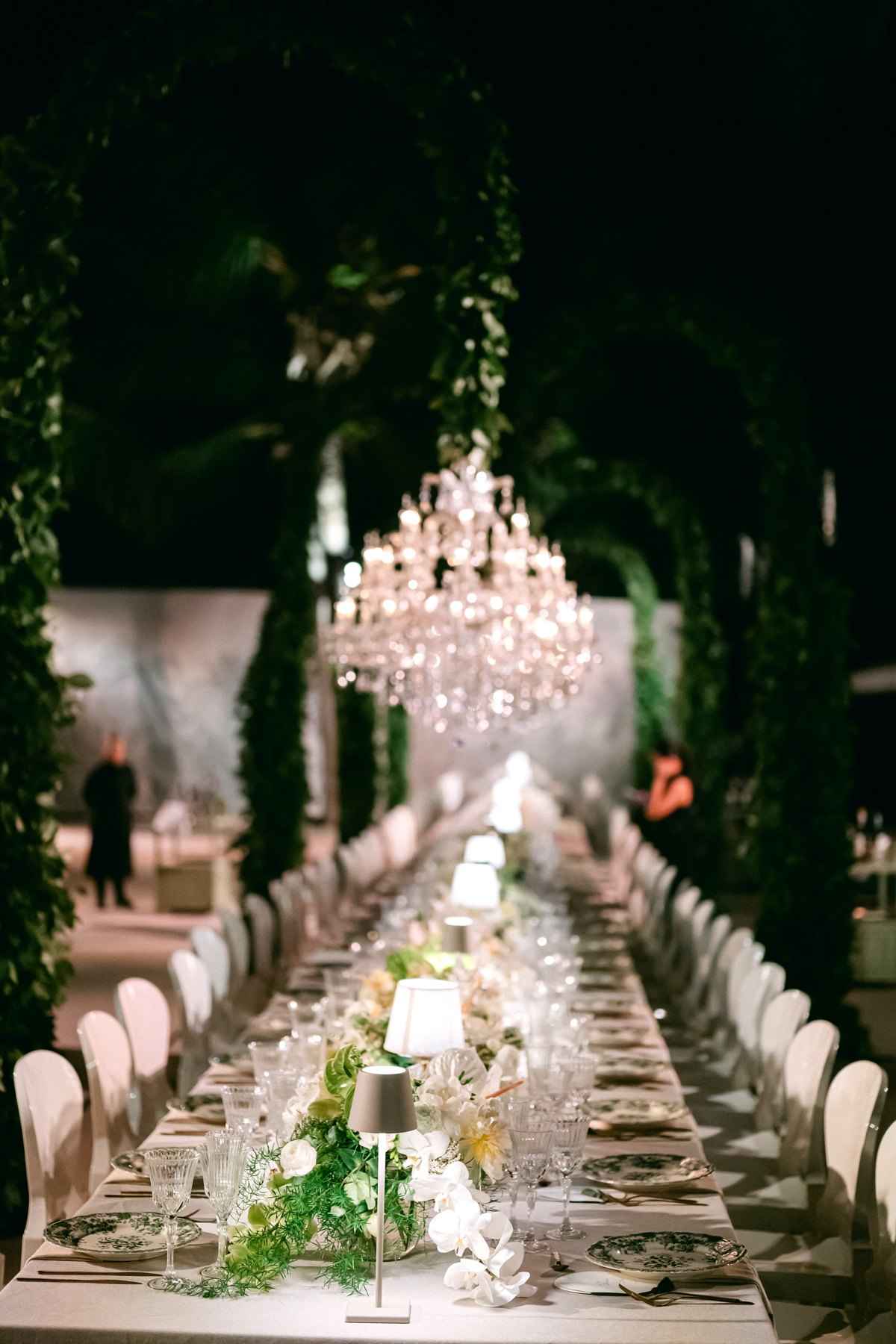 Crystal chandelier glowing above a candlelit beach wedding dinner at night, Curacao
