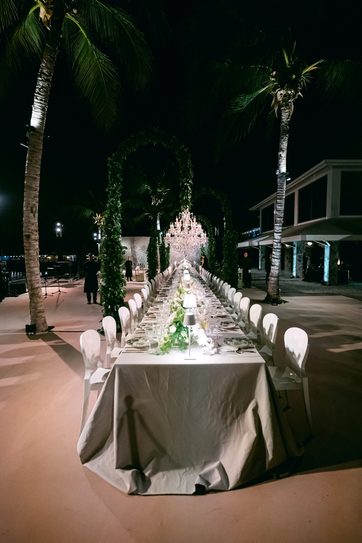 Long wedding dinner table at night with crystal chandelier centered above, Curacao