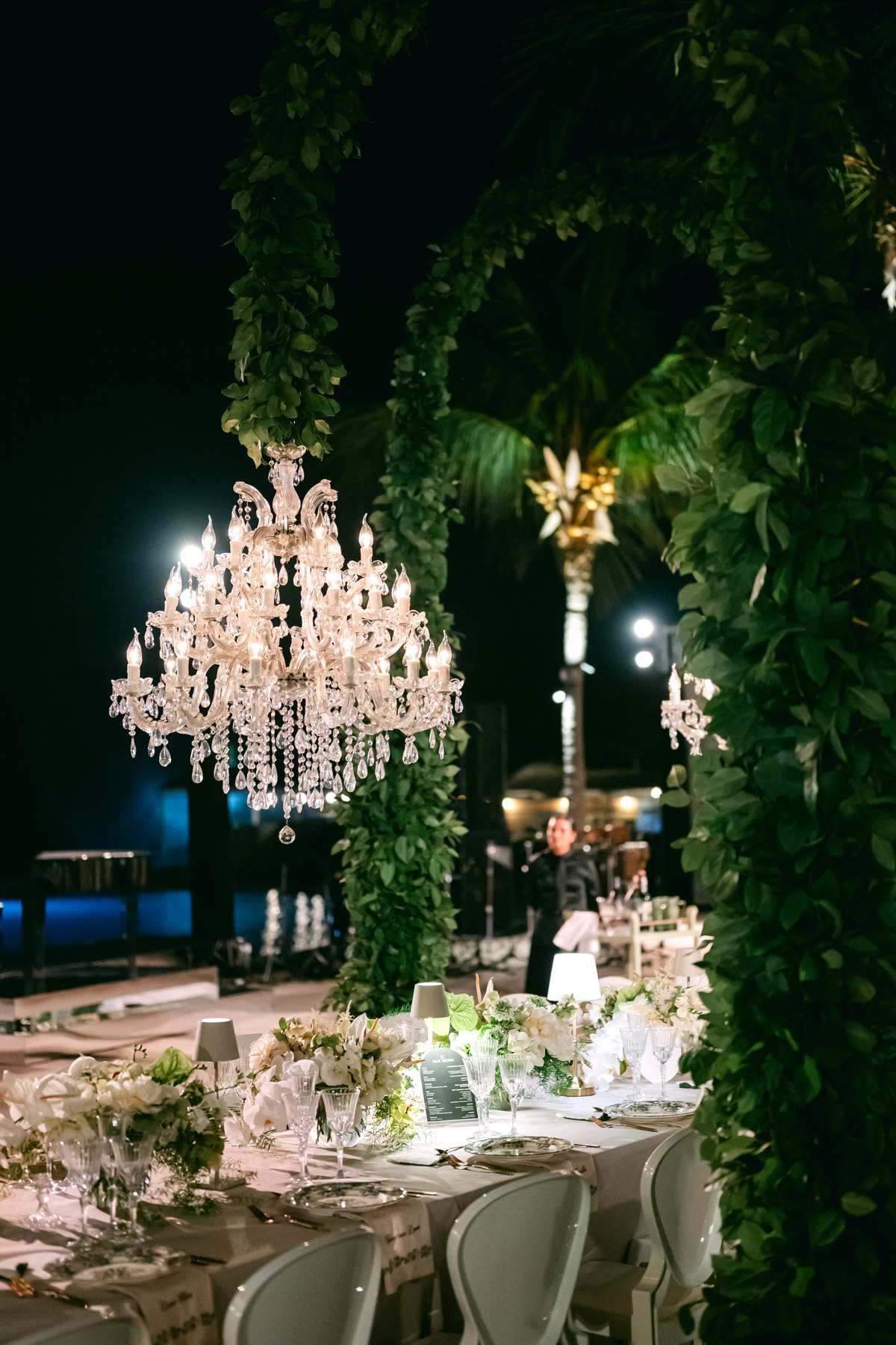 Maria Theresia crystal chandelier in a greenery arch at night with palms, Curacao